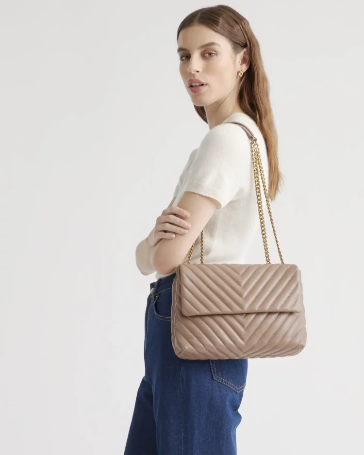 Quince Italian Leather Quilted Convertible Shoulder Bag in taupe on the shoulder of woman in a cream silk skirt