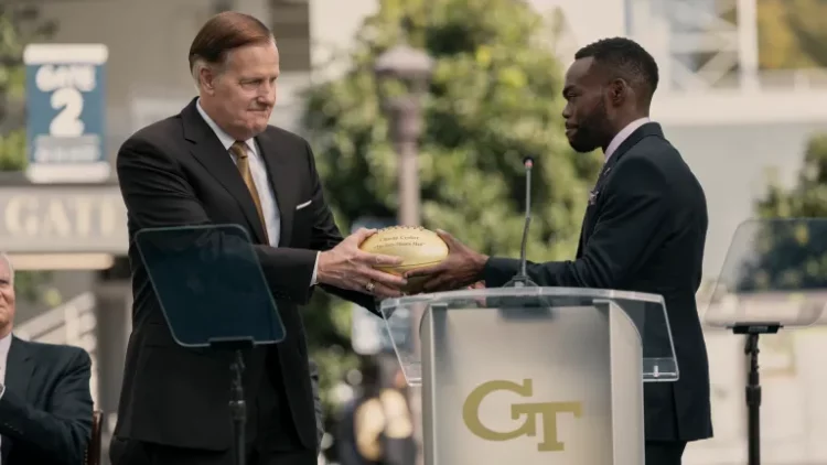 A Man in Full character Charlie Croker receiving a gold football from Mayor Wes Jordan