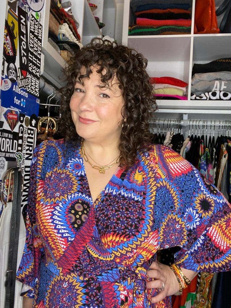 Charles Perri in a colorful printed blouse standing at the entrance to her closet