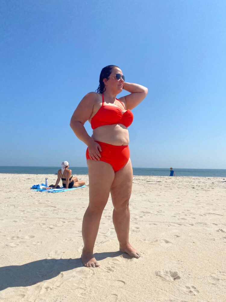 Woman in a bright orange bikini from the brand Smart & Sexy, standing on the beach