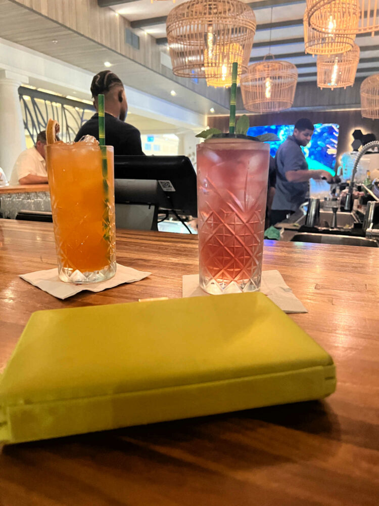 two colorful cocktails and a lime green satin clutch on the bar at the Curacao Marriott Beach Resort