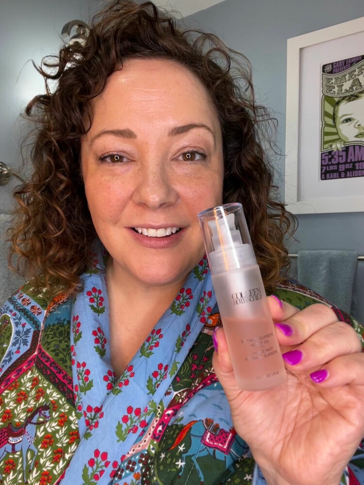 Charles Perri, the woman behind the over 40 style advice blog Wardrobe Oxygen, is holding a bottle of Colleen Rothschild Retinol Supreme Oil