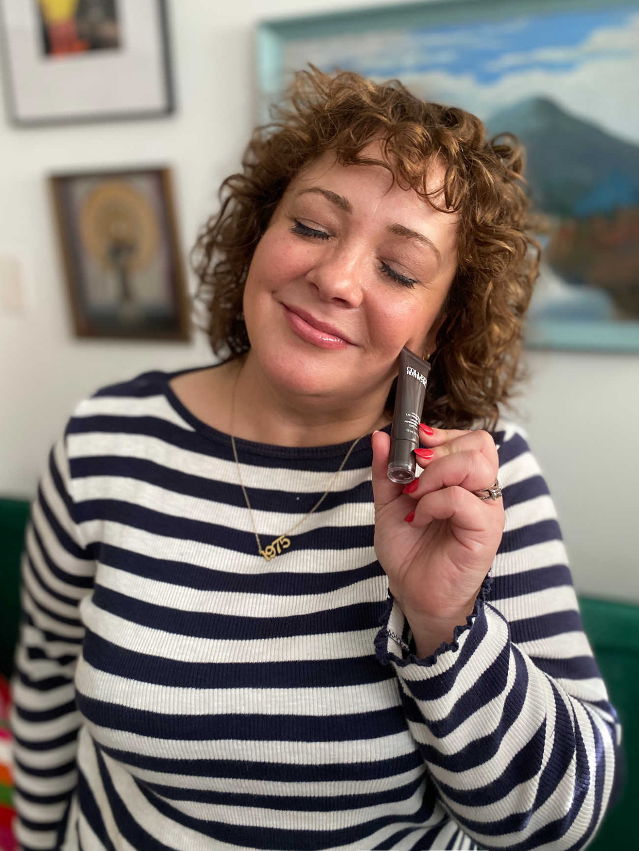 Charles Perri of Wardrobe Oxygen in a Breton striped top smiling and holing a Colleen Rothschild lip balm near her face, smiling