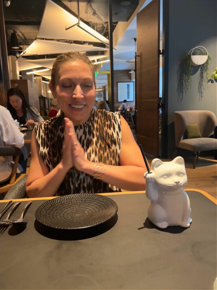 A woman at Michelin rated restaurant Cranes DC excited to drink a cocktail in a white glass shaped like a cat