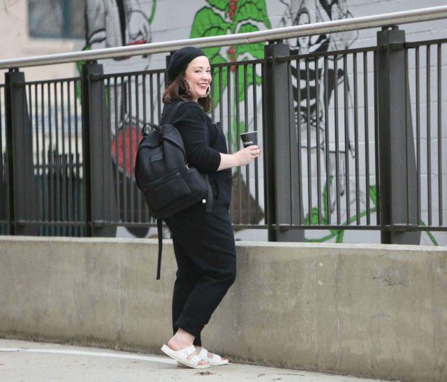 Universal Standard black overalls with a black cashmere sweater, EVA Birkenstocks, and the Dagne Dover Dakota backpack on Wardrobe Oxygen