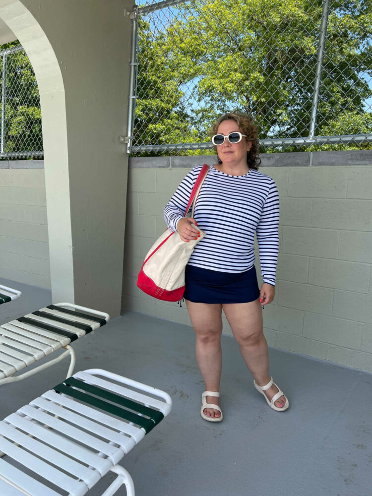 Alison of Wardrobe Oxygen in a striped rashguard and carrying a canvas tote with red straps.