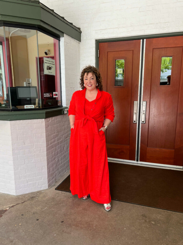 Charles Perri in the Universal Standard linen Promenade jumpsuit in orange with a matching linen tunic tied over it.