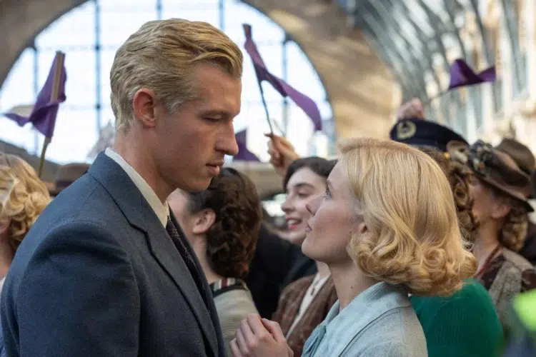 A scene from the movie The Boys in the Boat where character Joe and his girlfriend looking at one another in a train station.