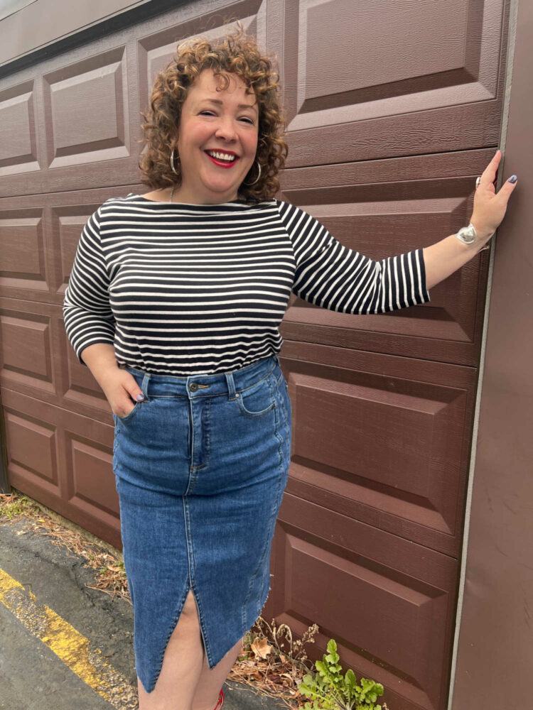 Woman wearing a black and white striped Breton with a denim skirt and red suede pumps