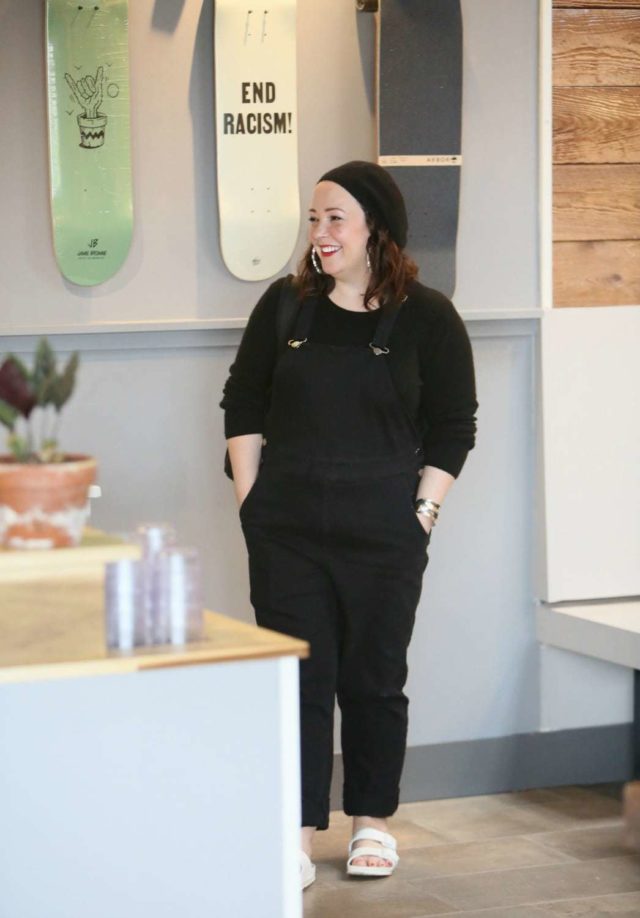 Universal Standard black overalls with a black cashmere sweater, EVA Birkenstocks, and the Dagne Dover Dakota backpack on Wardrobe Oxygen